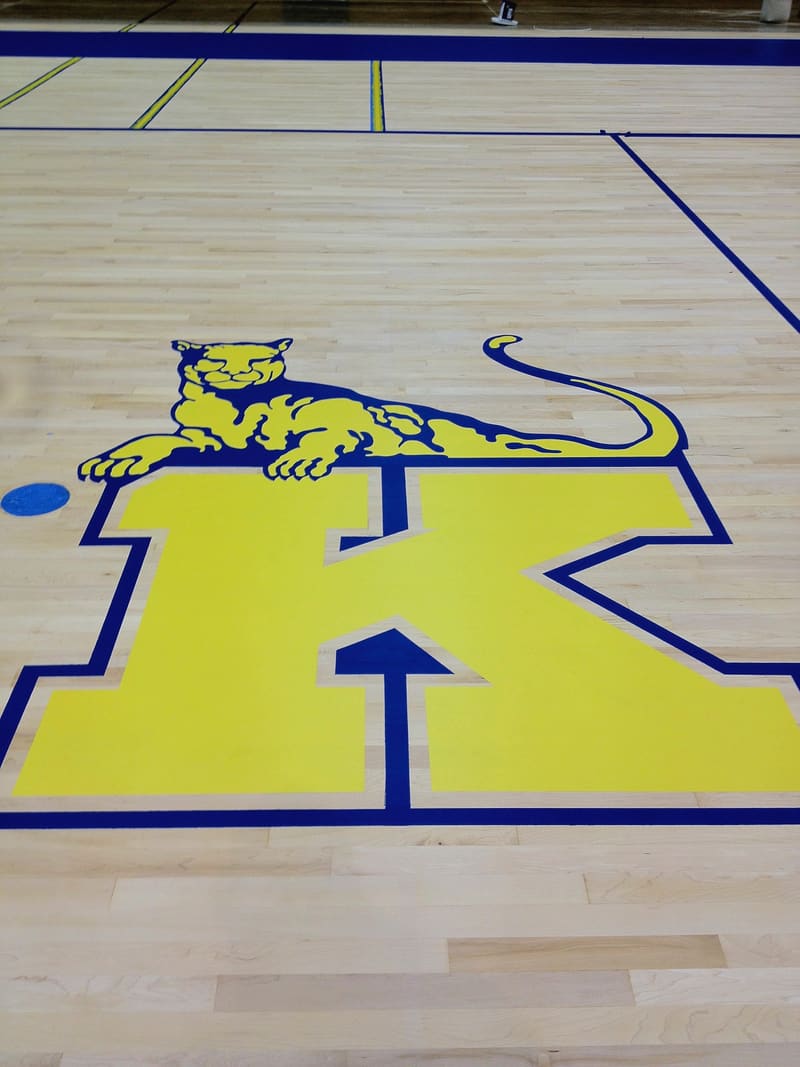 Gym floor painted with a yellow letter K and a wildcat mascot
